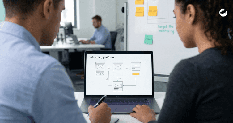Two colleagues review an e-learning platform's wireframes and data flow diagrams on a laptop, emphasizing rapid testing and validation in an office setting.